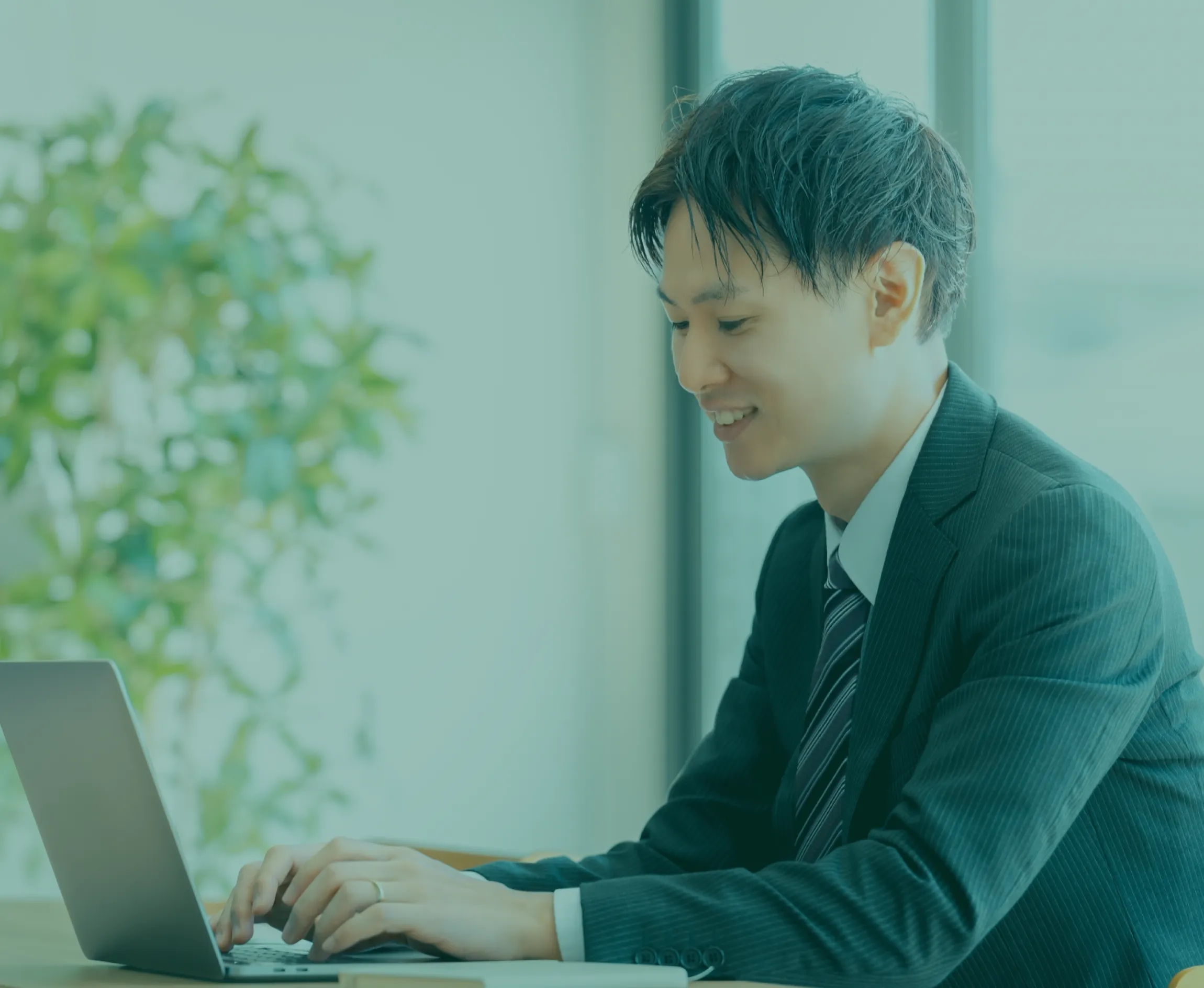 男性のビジネスマンが楽しそうにパソコン操作している画像